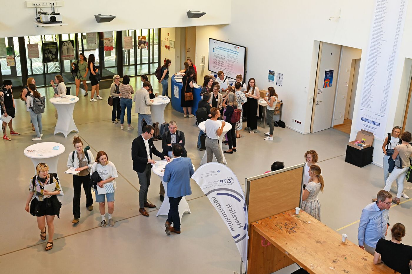 Symposiumsbesucher*innen stehen in Foyer in Grüppchen zusammen (Foto: Stefanie Gosejohann)