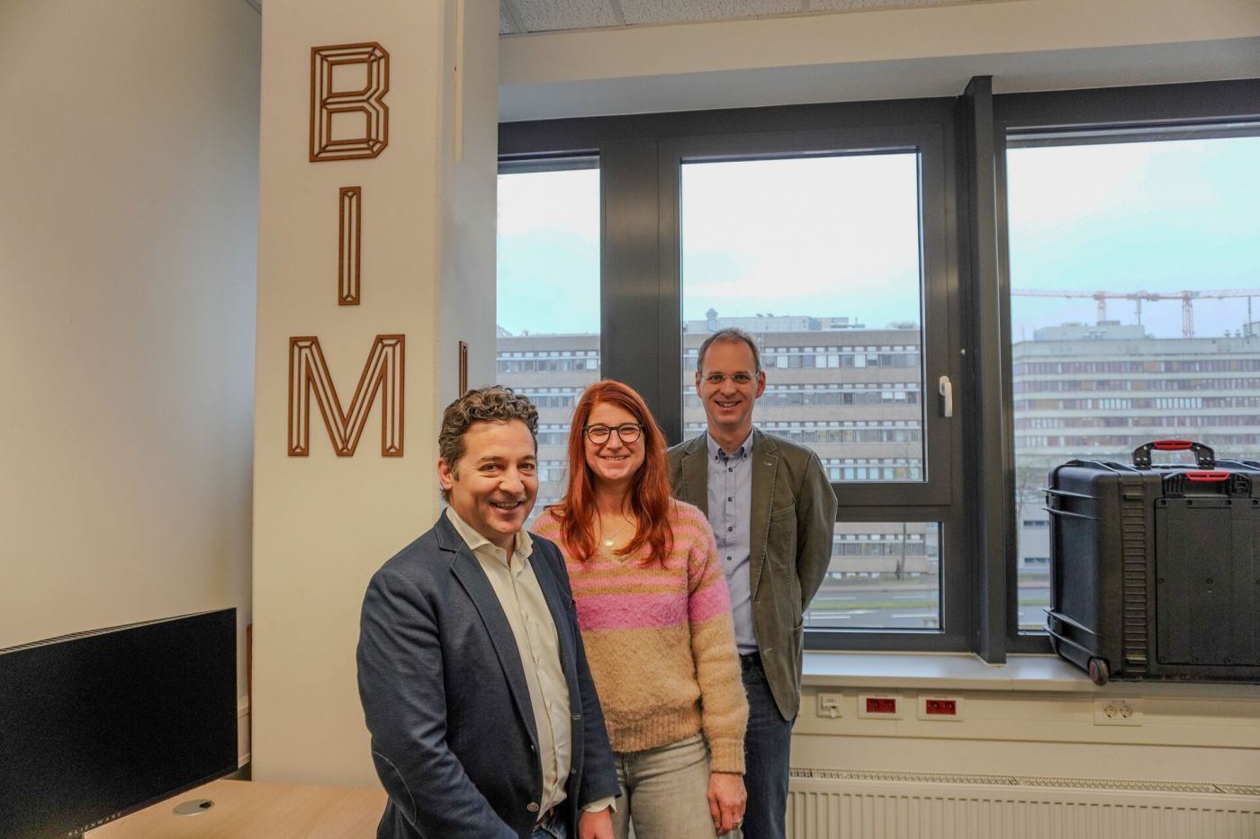 Drei Personen in einem Raum vor einem Schild auf dem BIM steht (Foto: FH Münster/Lucie Golde)