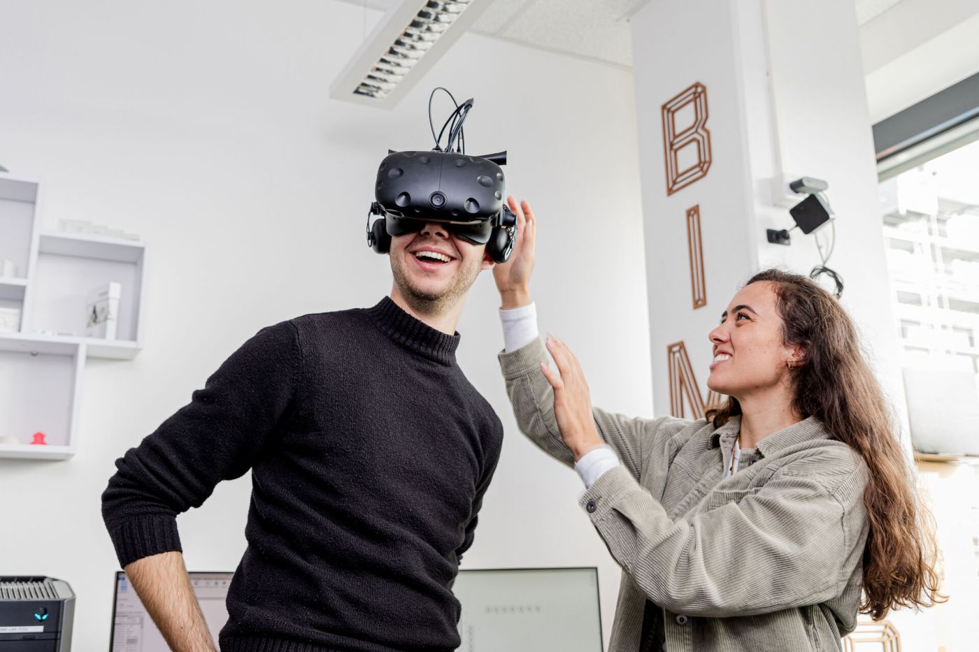 Ein Mann hat eine VR-Brille auf und eine Frau hilft ihm beim aufsetzen (Foto: Florian Kochinke)
