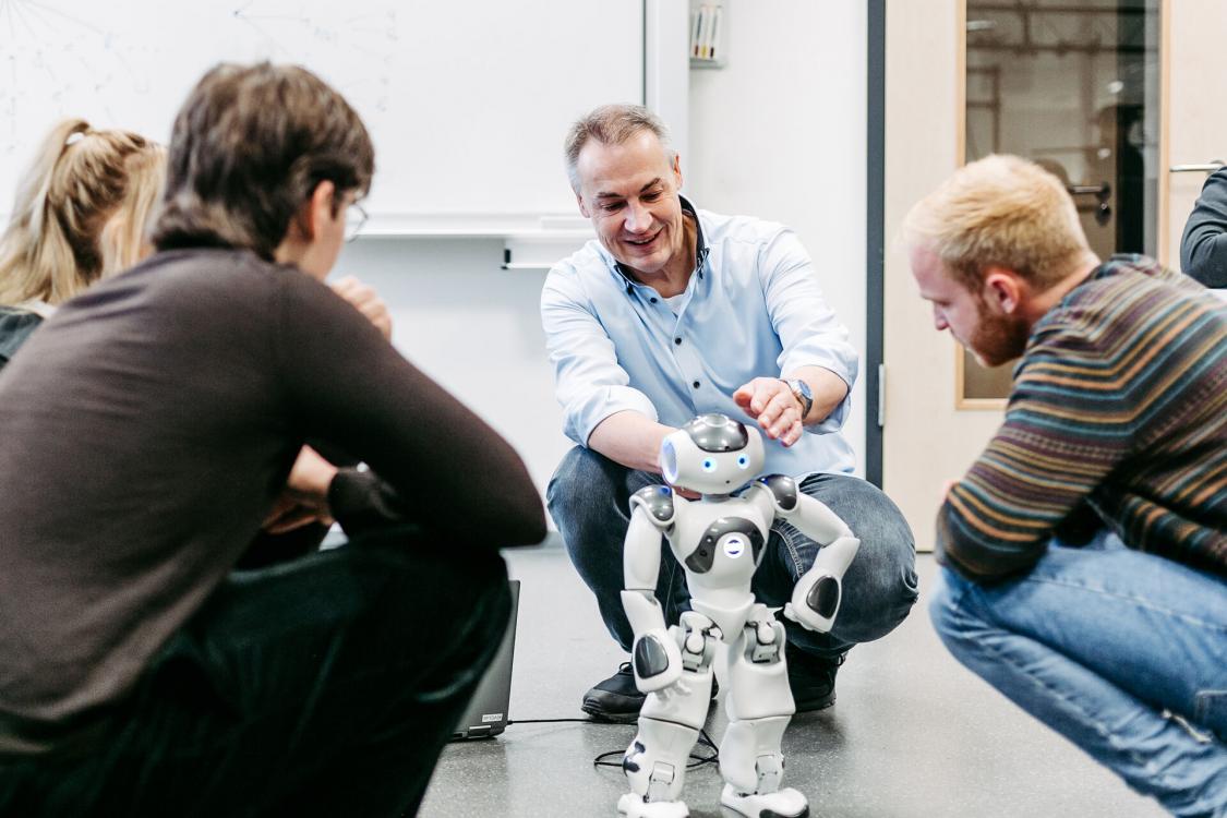 Prof. Jürgen te Vrugt programmiert mit Studierenden einen Roboter.