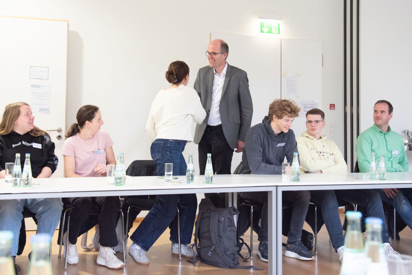Kanzler Guido Brebaum schüttelt junger Auszubildenden die Hand. Daneben sitzen fünf weitere Personen. (Foto: Stefanie Gosejohann)