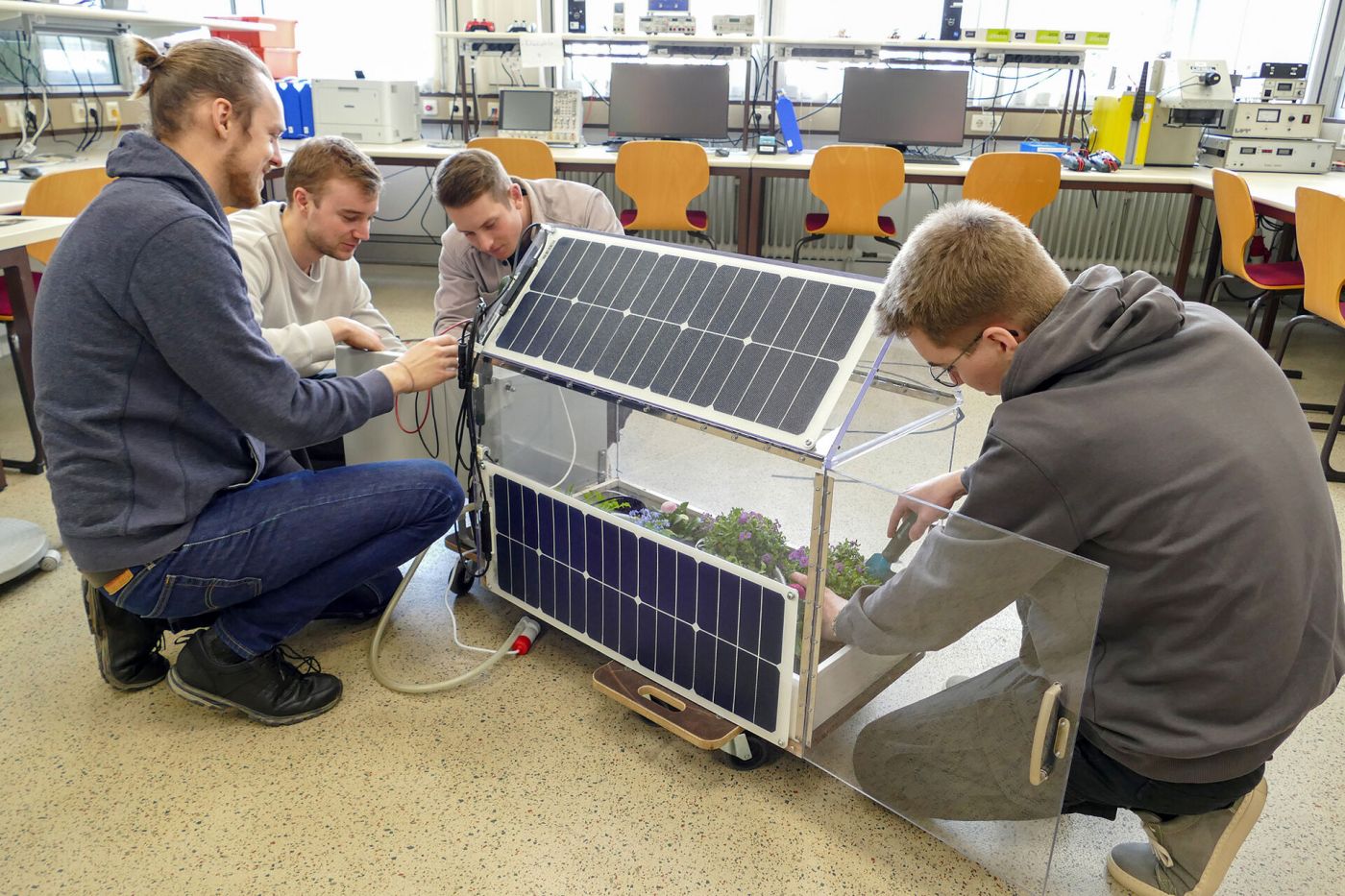 Vier Männer arbeiten in einem Labor an einem experimentellen Gewächshaus. (Foto: FH Münster/Jana Bade)