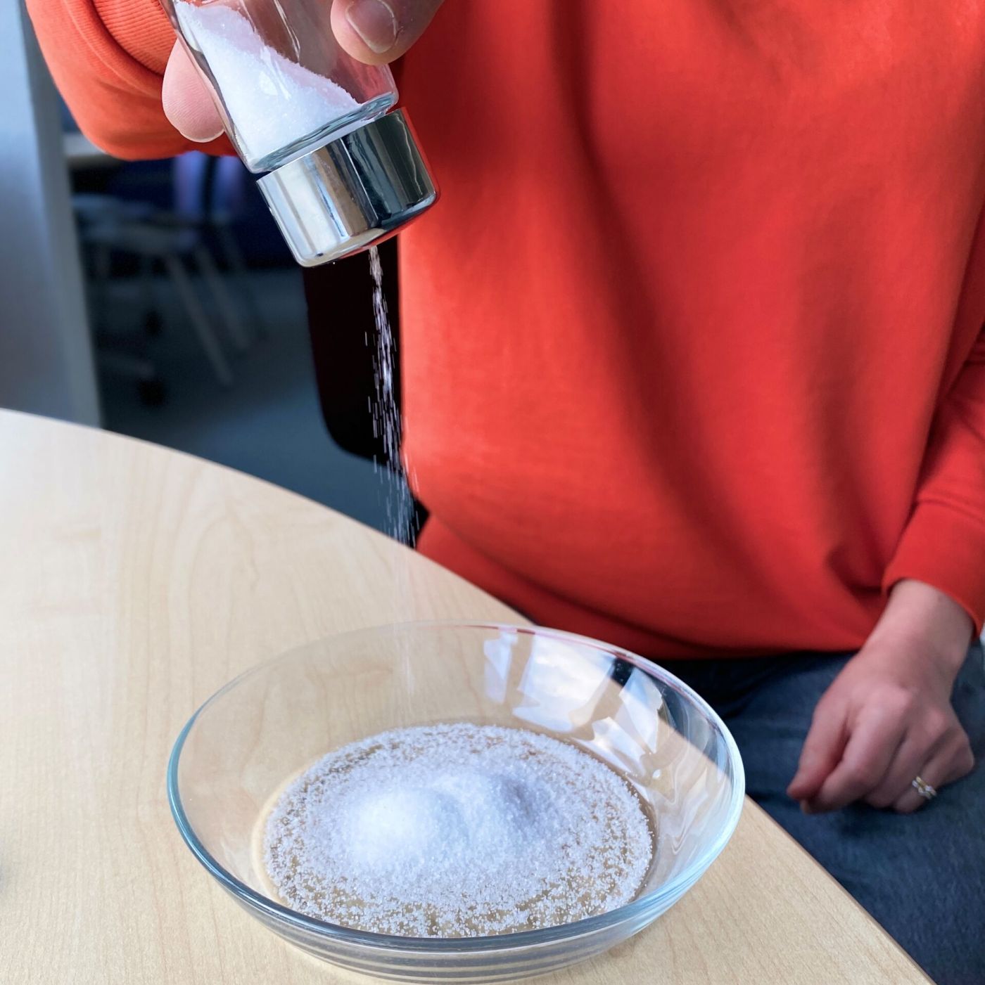 Eine Person streut viel Salz in einen Teller. 