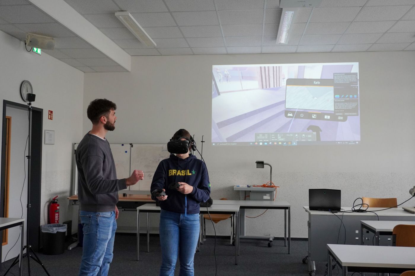Eine Schülerin mit VR-Brille, daneben steht ein Mann der etwas erklärt. (Foto: Foto: FH Münster/Lucie Golde)