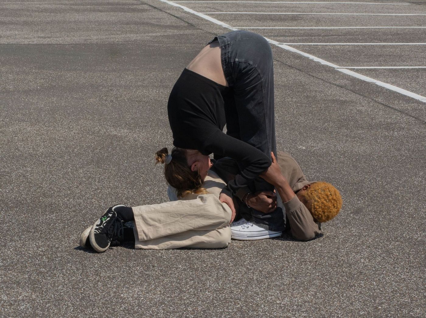 Zwei ineinander verknotete tanzende junge Menschen auf dem Asphaltboden eines Parkplatzes. 