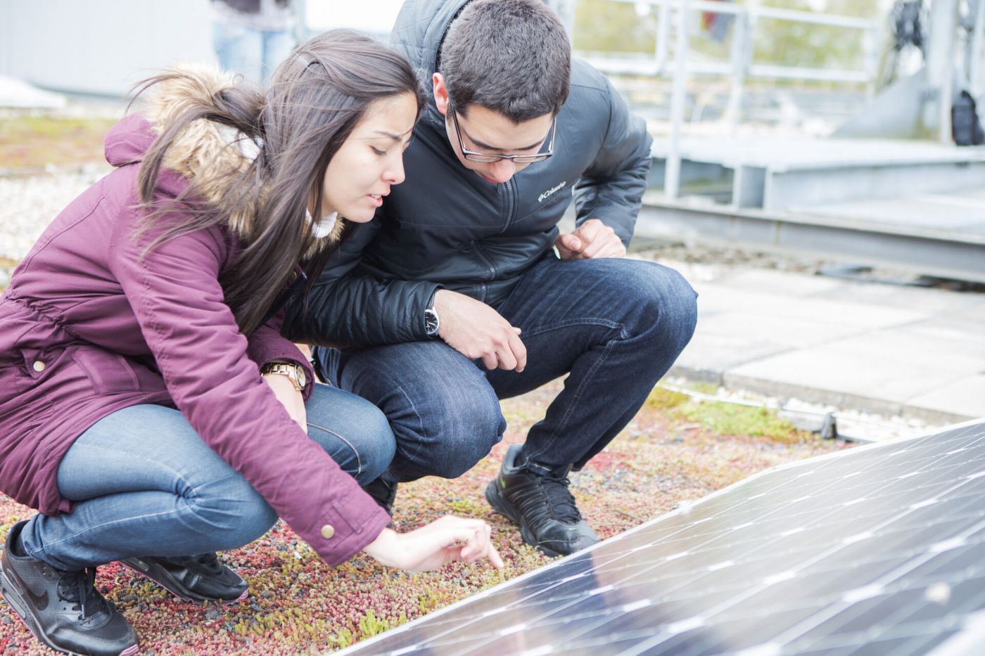 Eine Frau und ein Mann schauen auf eine Photovoltaikanlage.
