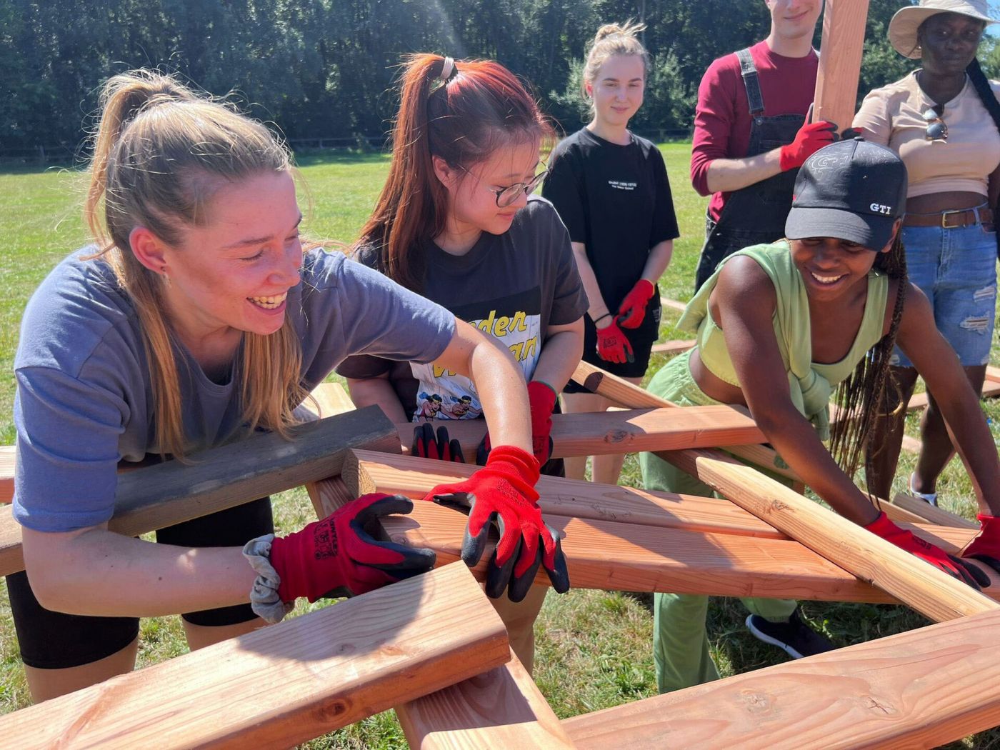 Eine Gruppe von Studierenden baut aus Holzplanken eine Brücke im Freien. (Foto: Prof. Felix Beck)