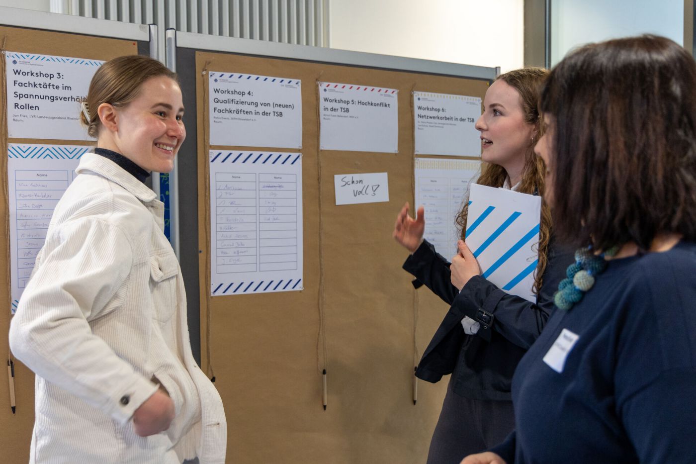 Teilnehmer*innen des Fachtags stehen vor einer Pinnwand und tragen sich eine Liste ein (Foto: FH Münster/Anna Thelen)