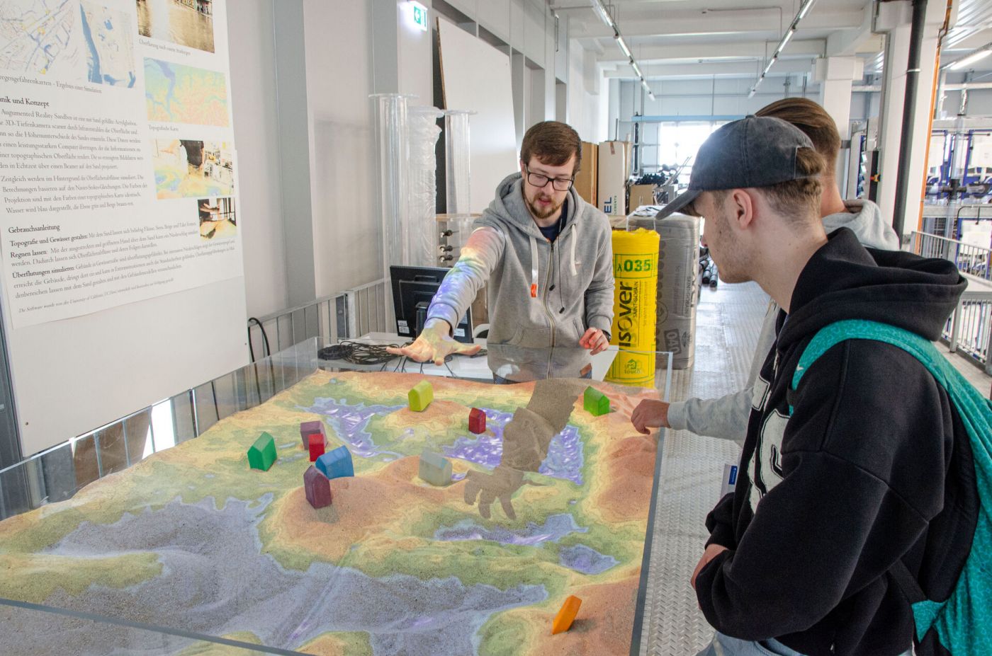 Drei Männer arbeiten mit einer Augmented Reality Sandbox. (Foto: FH Münster/Frederik Tebbe)