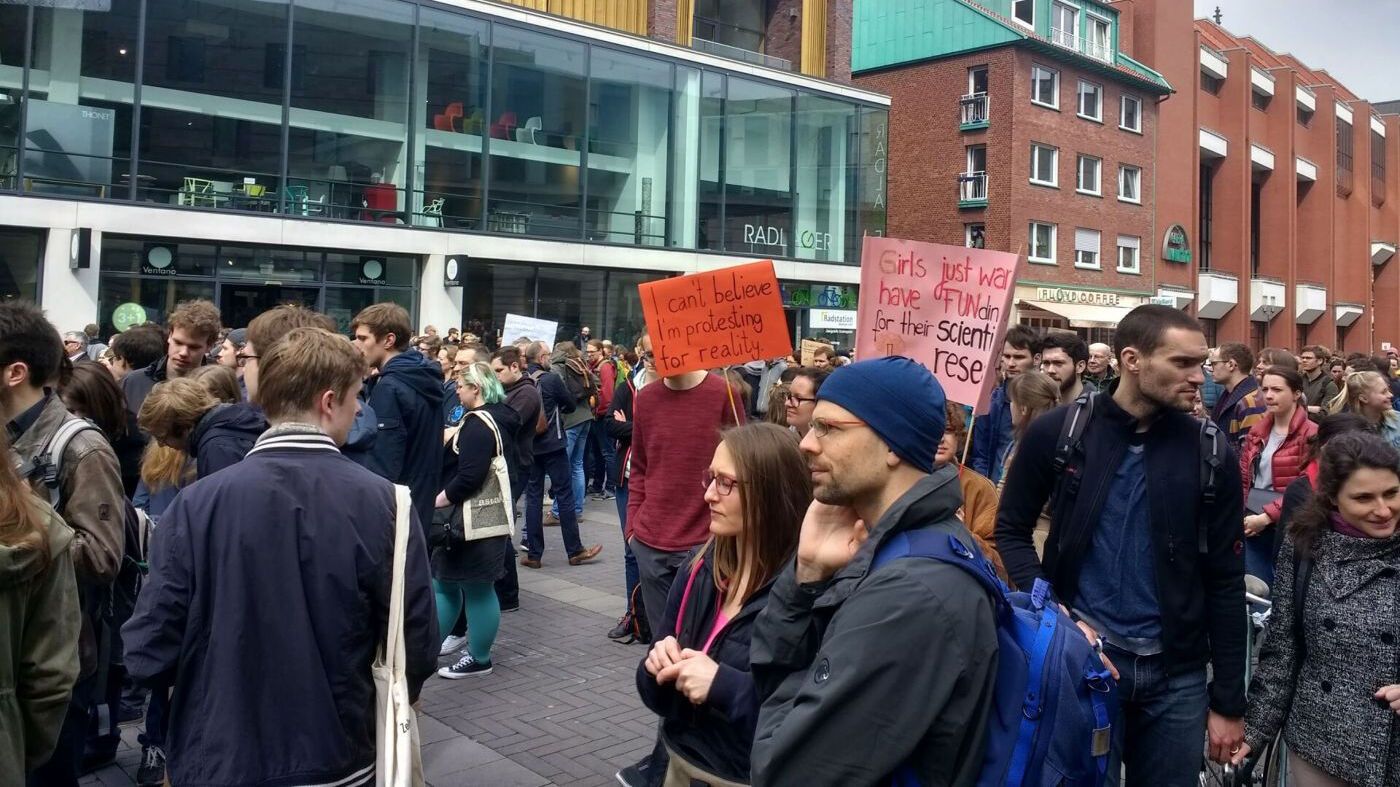Eine Gruppe von Personen, die auf einer Demonstration auf die Bedeutung von Wissenschaft aufmerksam machen und Poster hoch halten. (Foto: WWU/Johannes Sträßer)