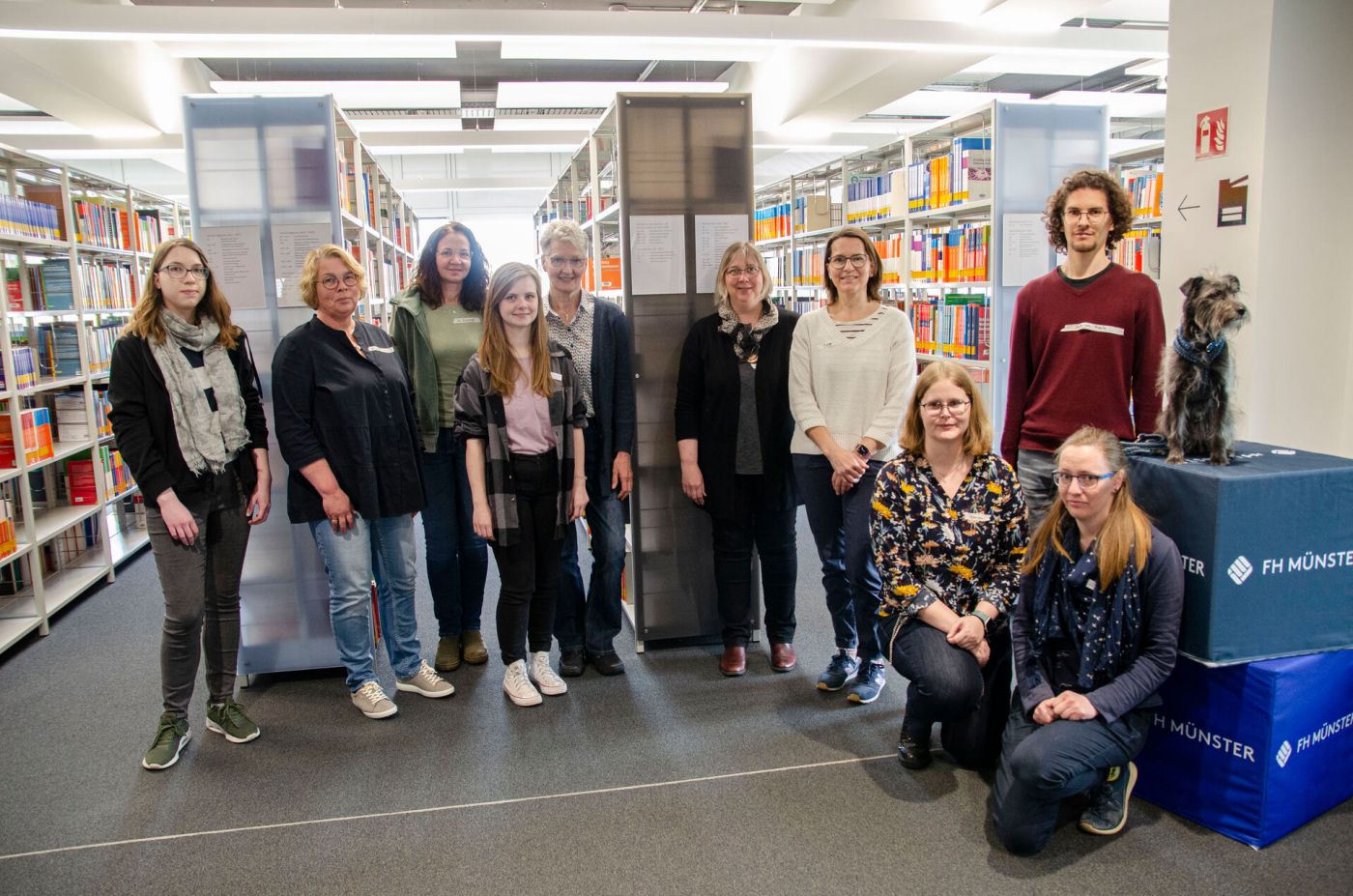 Neun Frauen und ein Mann stehen in einer Bibliothek. (Foto: FH Münster/Frederik Tebbe)