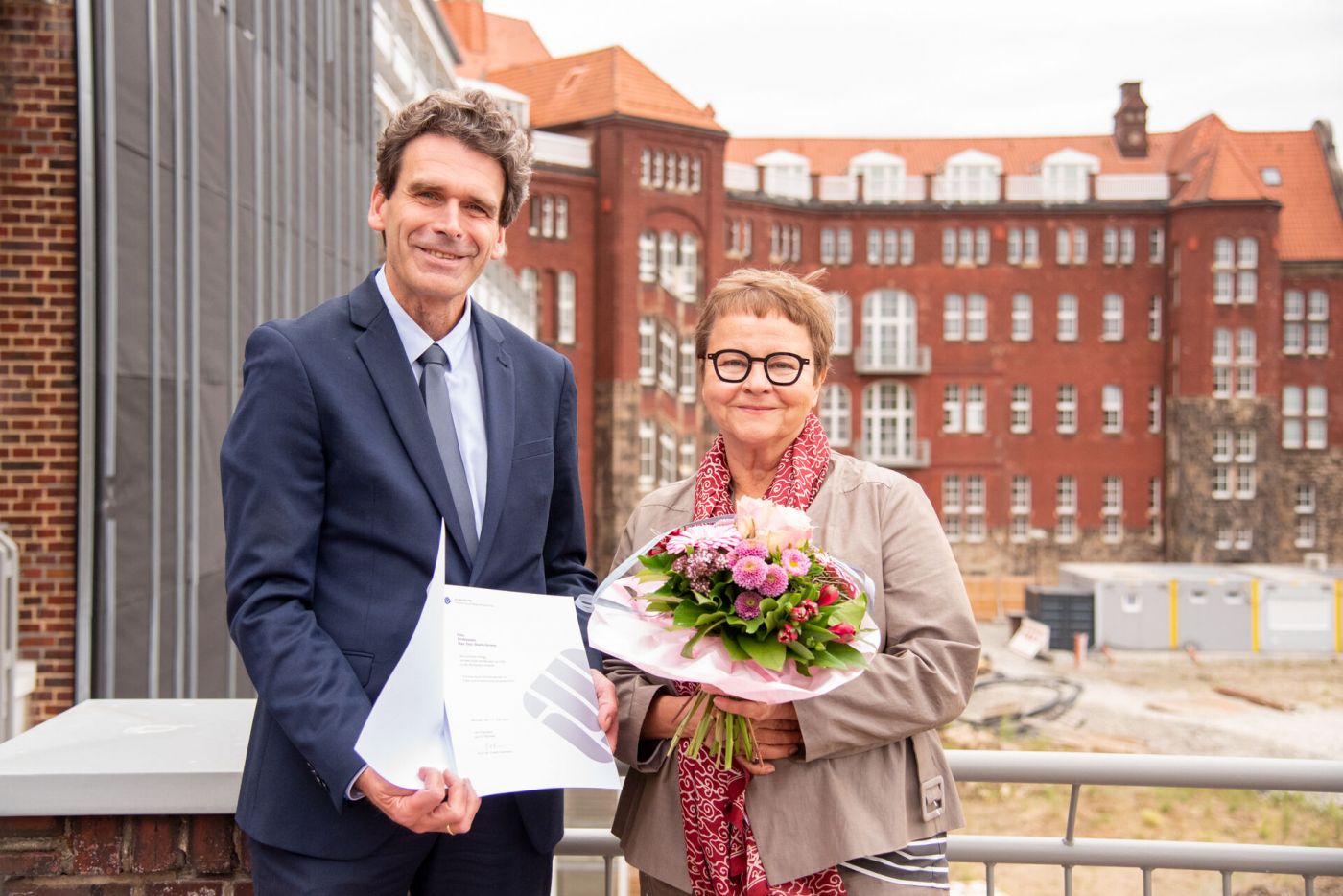 Zwei Personen mit einer Urkunde und einem Blumenstrauß (Foto: FH Münster/Michelle Liedtke)