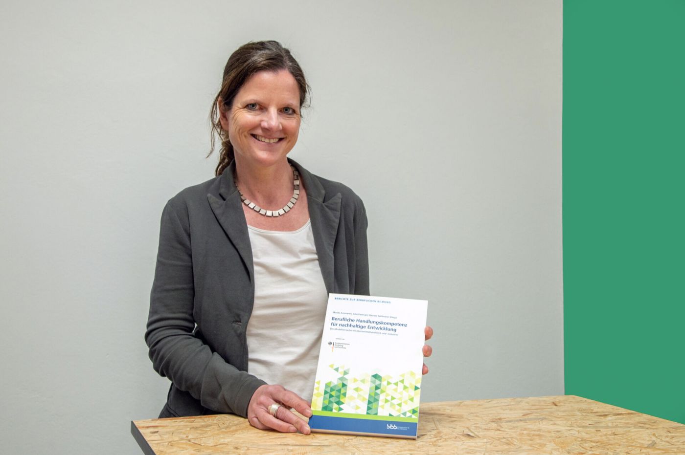 Eine Frau hält ein Buch zu Nachhaltigkeit im Lebensmittelhandwerk. (Foto: FH Münster/Michelle Liedtke)
