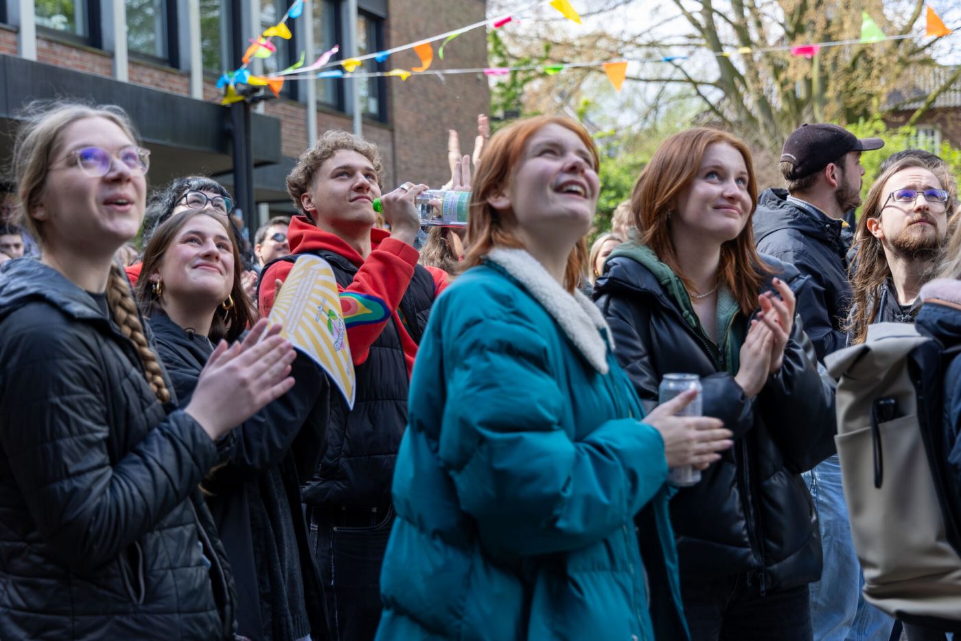 Eine Gruppe Studierender steht vor einem Gebäude und klatscht lächelnd in die Hände (Foto: FH Münster/Anna Thelen)