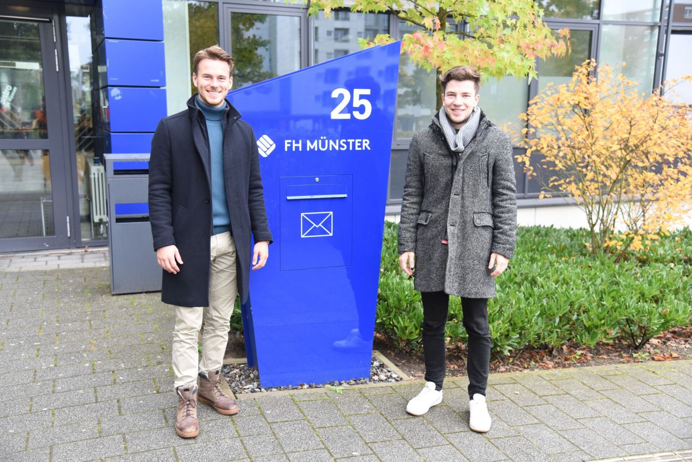 Zwei Studenten stehen vor einem Hochschulgebäude (Foto: FH Münster/Frederik Tebbe)