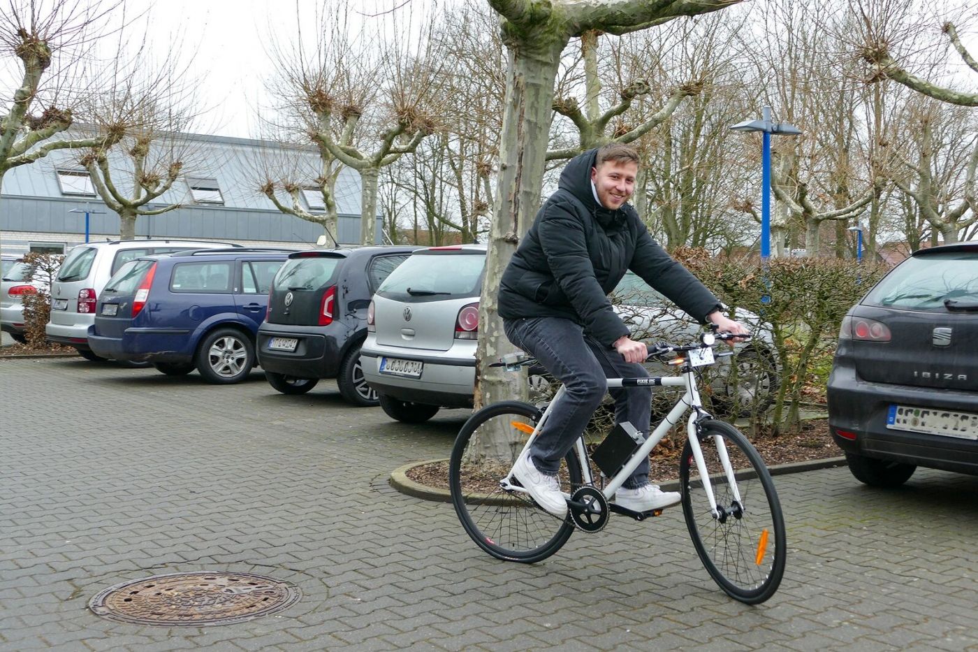 Ein Mann fährt mit einem Fahrrad über einen Parkplatz. (Foto: FH Münster/Jana Bade)