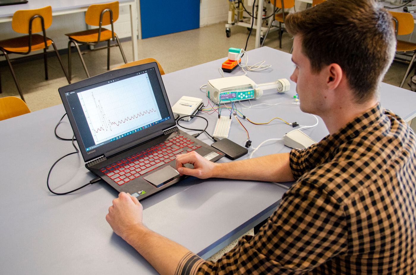 Ein Student arbeitet an einem Laptop, auf dem ein Graph abgebildet ist. 