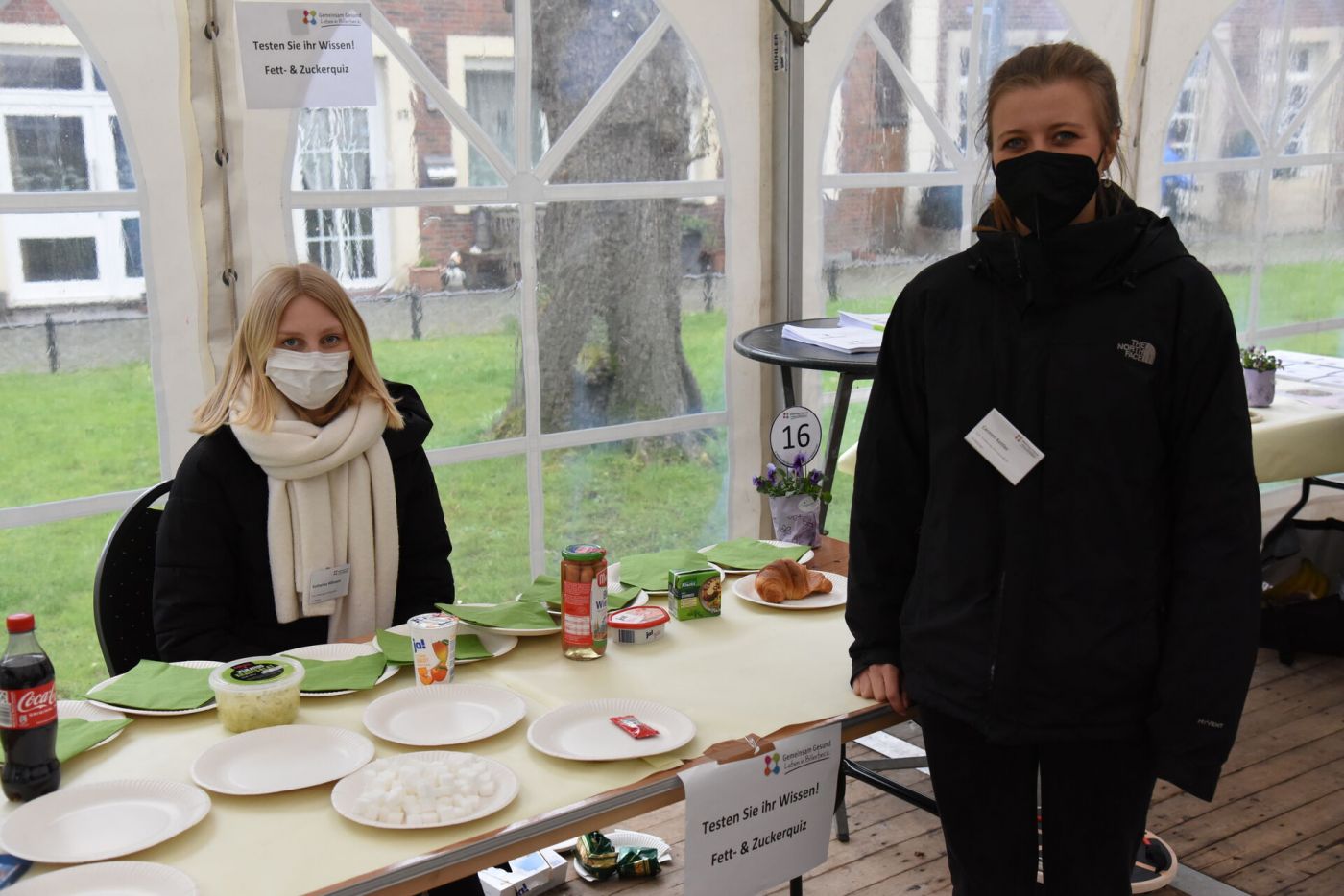 Zwei Frauen an einem Tisch, auf dem verschiedene Lebensmittel und Zuckerwürfel platziert sind. (Foto: FH Münster/Frederik Tebbe)