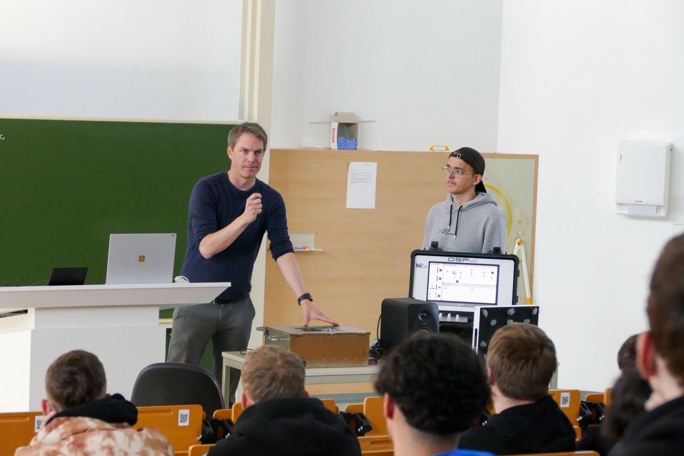 Ein Professor und ein Student halten einen Vortrag in einem Hörsaal.