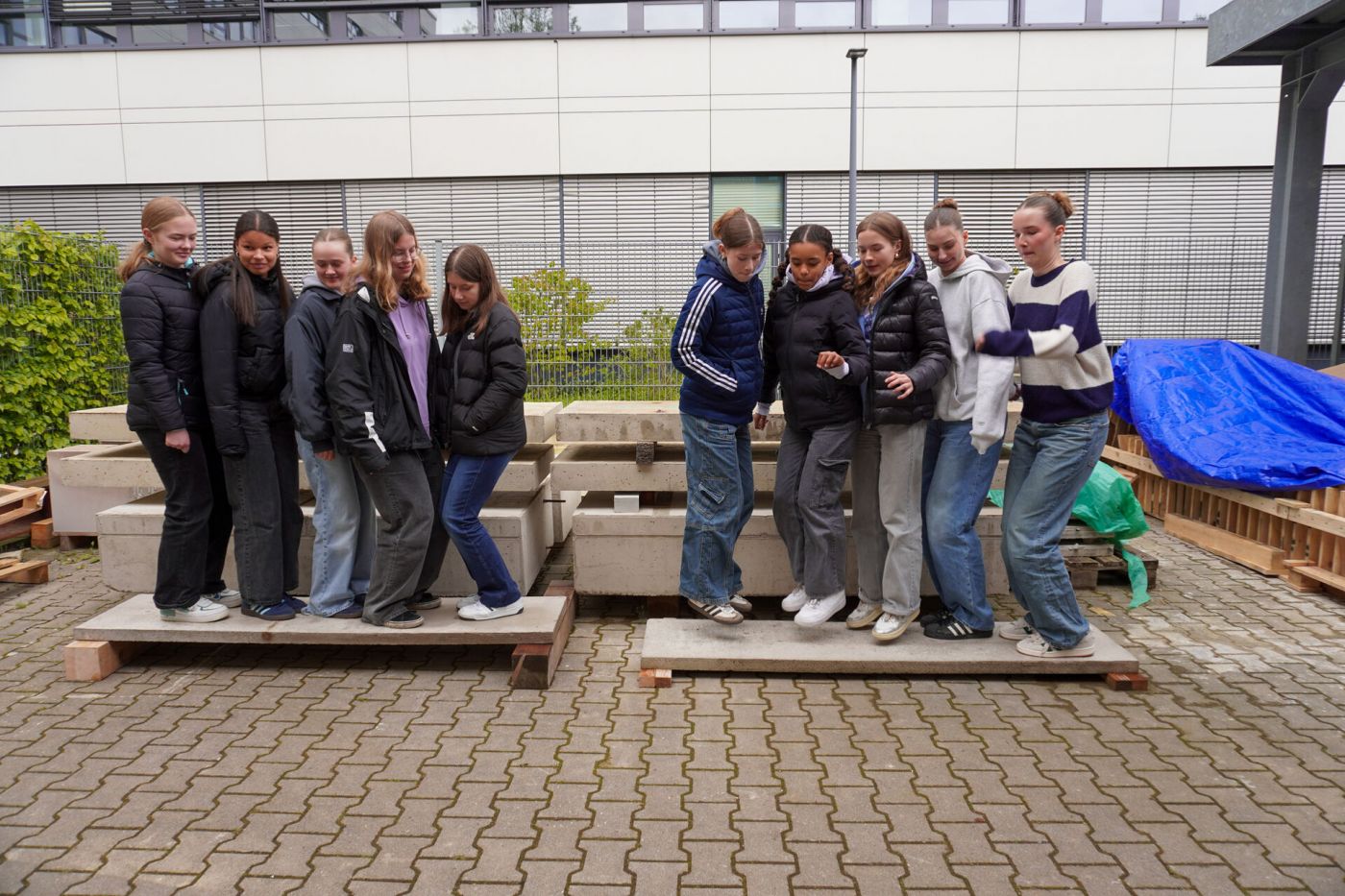 Jeweils vier Schülerinnen stehen auf einer Betonplatte und springen hoch. (Foto: Foto: FH Münster/Lucie Golde)