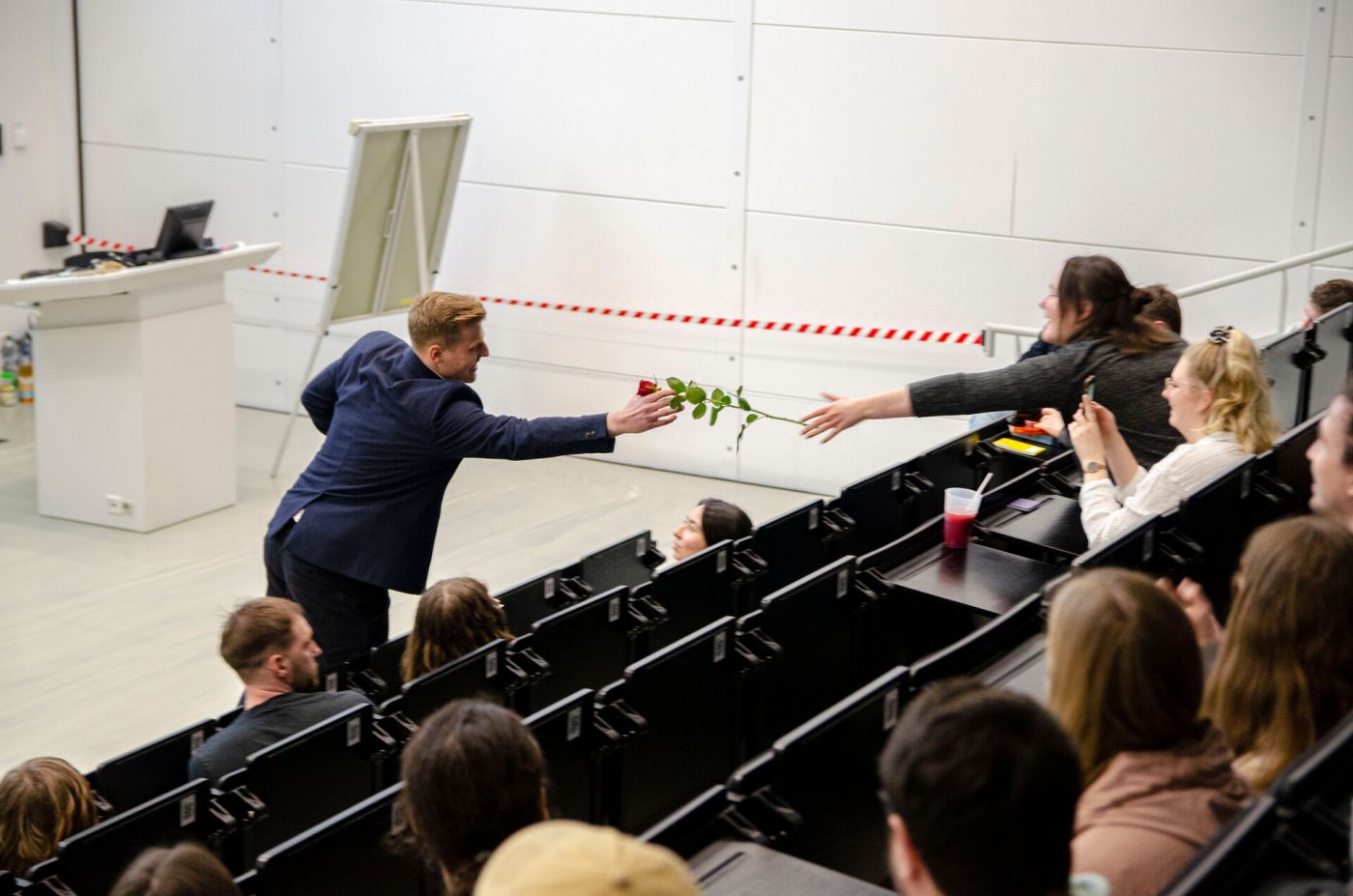 Ein Mann überreicht einer Frau im Hörsaal eine Rose. (Foto: FH Münster/Frederik Tebbe)