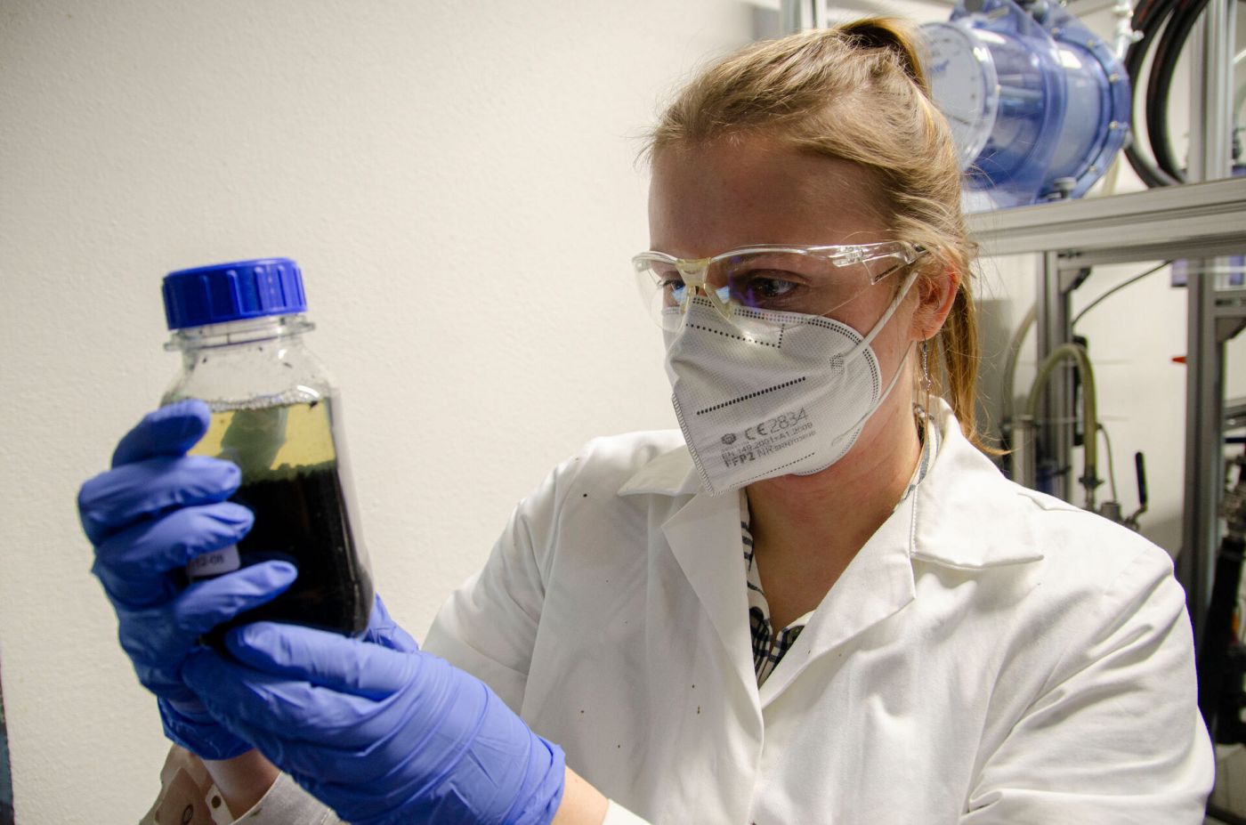 Eine junge Frau in Laborkittel hält in einer kleinen Flasche eine Probe in den Händen. (Foto: FH Münster/Frederik Tebbe)