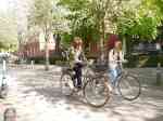 Zwei Studentinnen fahren mit dem Fahrrad auf einem Campusgelände.