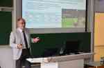 Ein Professor hält einen Vortrag, im Hintergrund ist eine Präsentation zum Klimawandel zu sehen. (Foto: FH Münster/Frederik Tebbe)