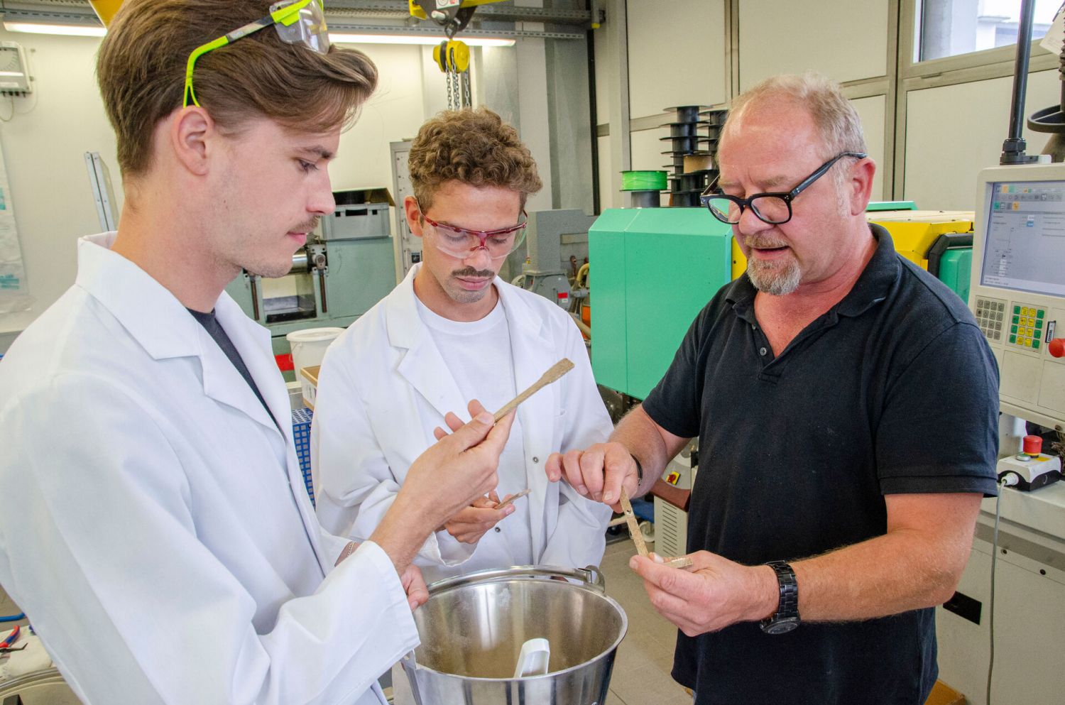 Drei Männer begutachten die Ergebnisse ihrer Arbeit in einem Labor. Der erste Versuch ist geglückt (v. l.): Bence, Calvin und Martin halten die Schulterstäbe aus Bagasse und Bio-Kunststoff in den Händen. 