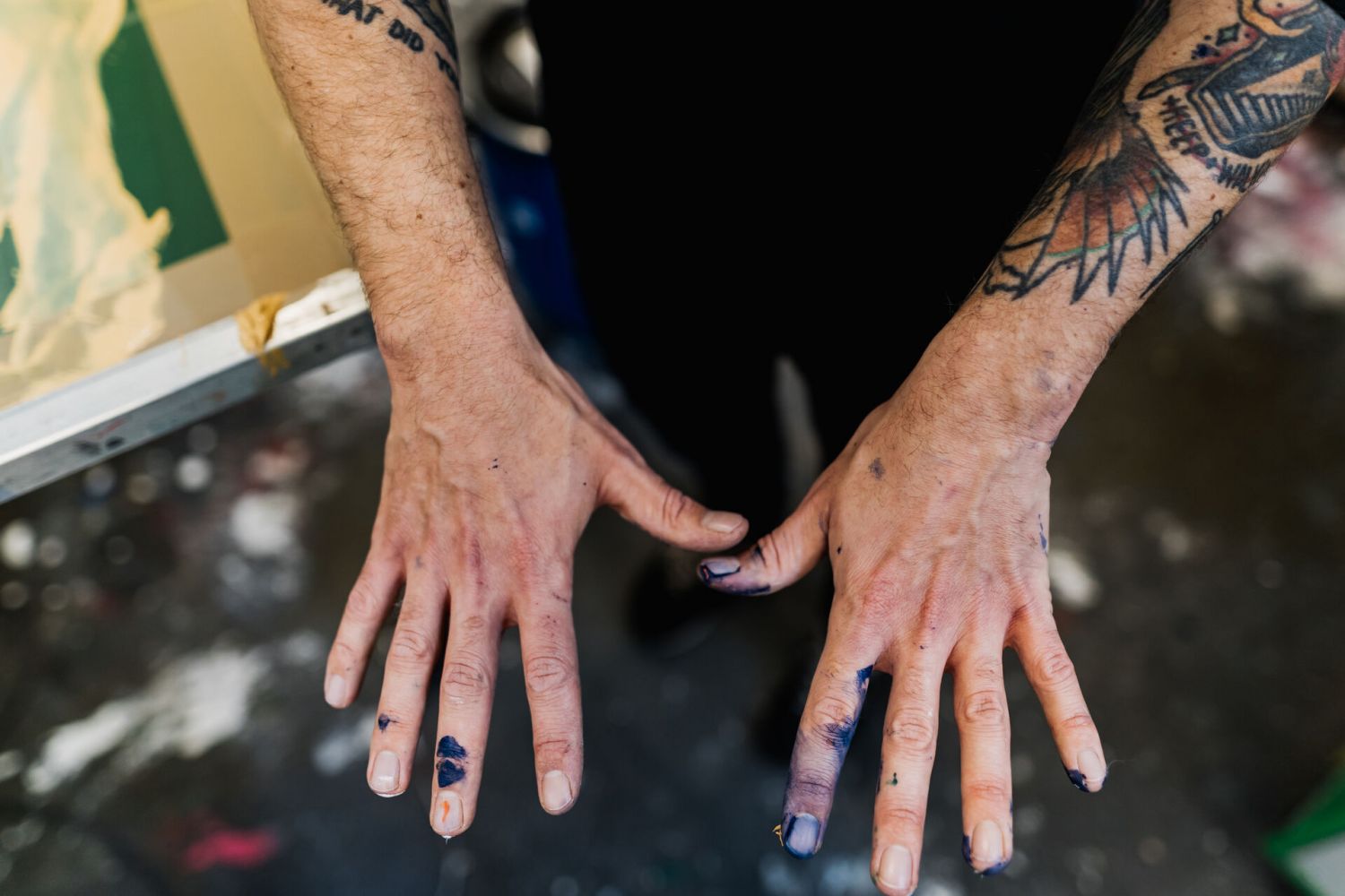 Ein Mann streckt seine Hände aus, die schmutzig von Druckfarbe sind.