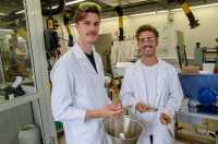 Zwei Männer stehen mit Kittel und Schutzbrille in einem Labor.